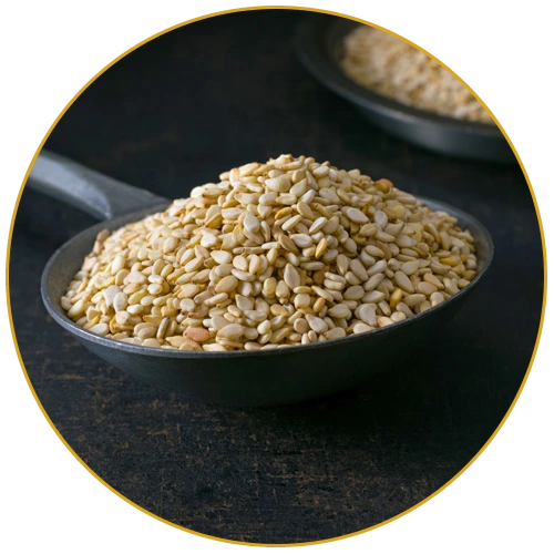 unhulled white sesame seeds on ladle on a dark background with circular border